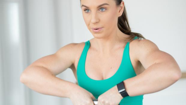 India wears turquoise work out gear and is lifting a kettlebell with two hands, showing her strength