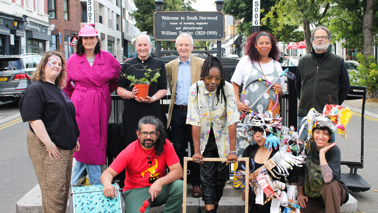 Photo of group of people standing in front of a sign for William Stanley.
