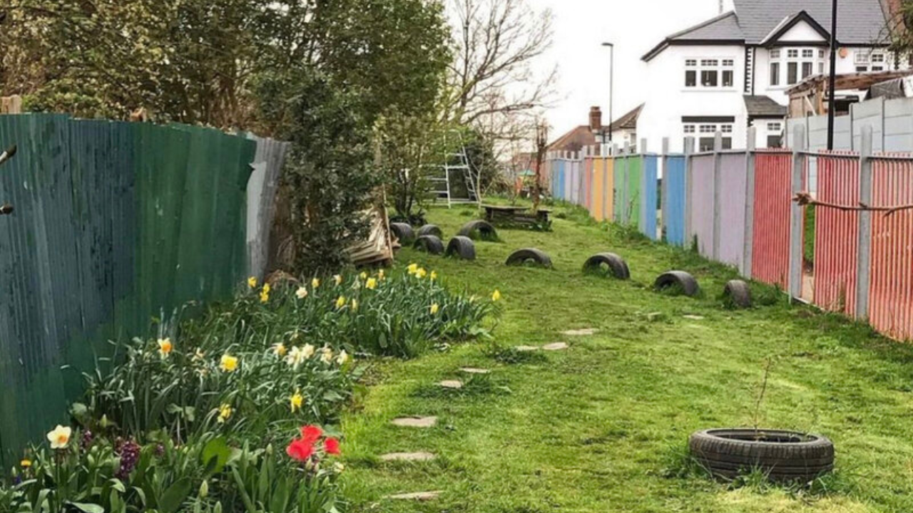 Love Lane Green. Houses in background with corrugated fences bordering the green.