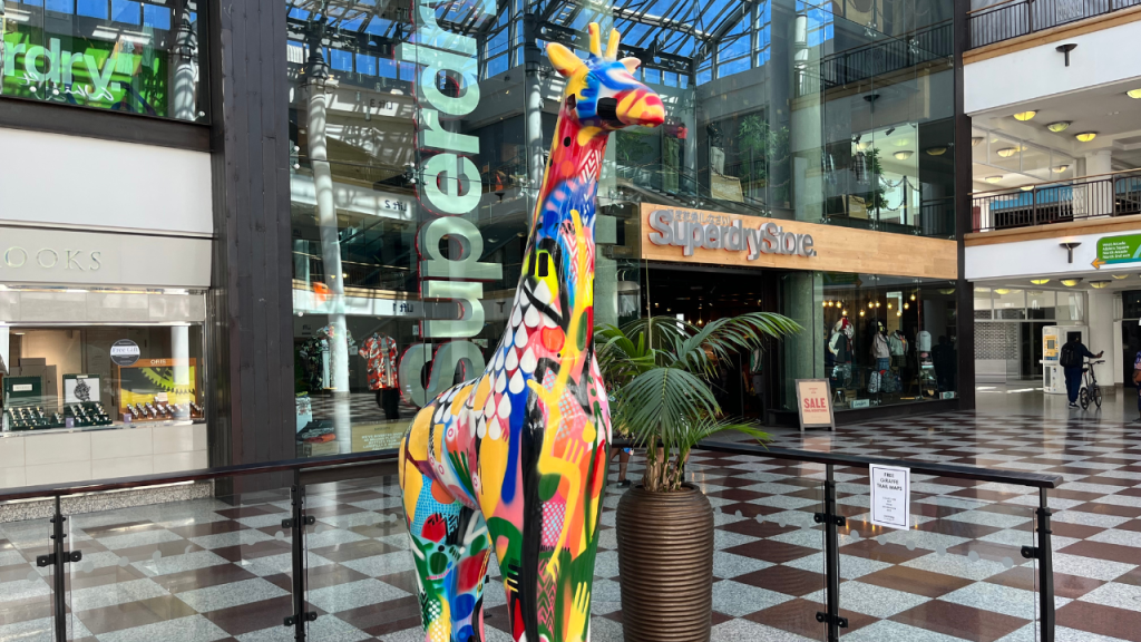 Giant giraffe sculpture in the Whitgift Centre in front of Superdry Store.