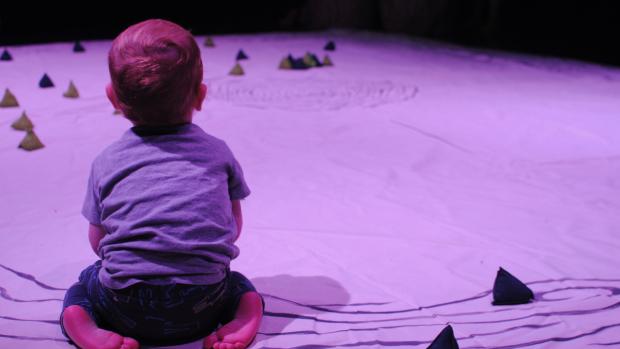Picture of a baby from behind, sitting on a white map.