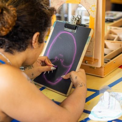 A woman using chalks to create a self portrait