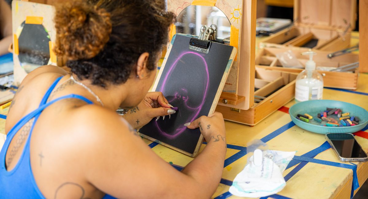 A woman using chalks to create a self portrait