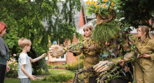 A boy holds his hand out to the Dandelion man