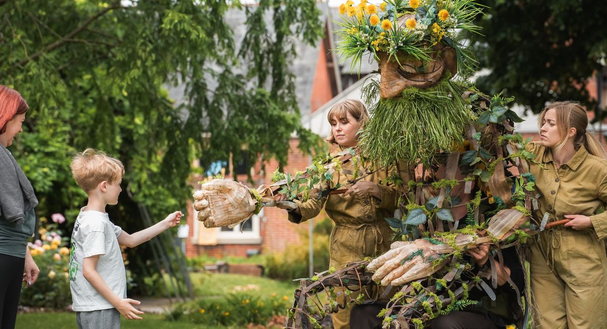 A boy holds his hand out to the Dandelion man