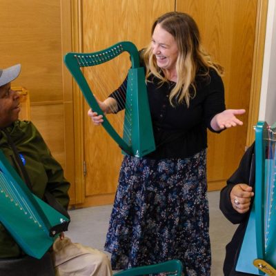 Adults try out miniature harps with support from a professional harpist