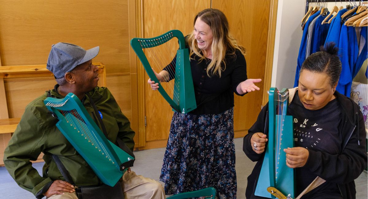 Adults try out miniature harps with support from a professional harpist