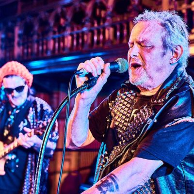 A man singing into a microphone in Croydon's Braithwaite Hall