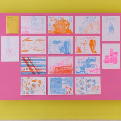 A display of artworks on a vibrant pink and yellow backdrop