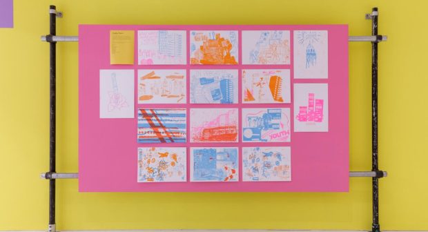 A display of artworks on a vibrant pink and yellow backdrop