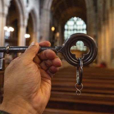 A hand holding up a giant key inside Croydon Minster