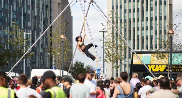 A circus performer is suspended in the air above a crowd of people